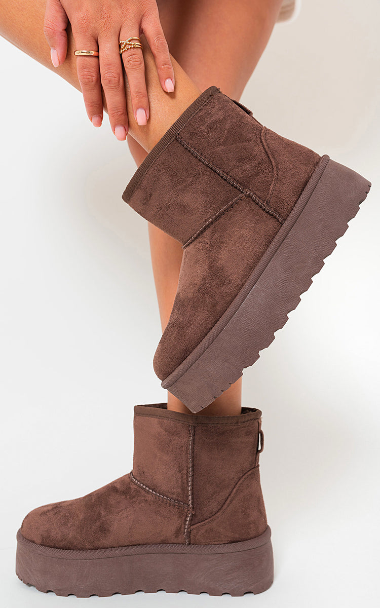 Brown thick-heel platform boots with suede upper and faux-fur lining, worn on white background